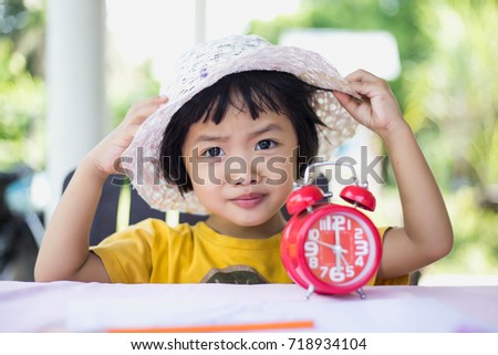 Little asian girl holding toy clock school time