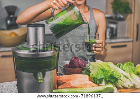 Woman juicing making green juice with juice machine in home kitchen. Healthy detox vegan diet with vegetable cold pressed extractor to extract nutrients for smoothie drink. Royalty-Free Stock Photo #718961371