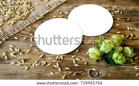 Two blank beer coasters on wooden rustic table background with cloth burlap, barley and hops. Idea for new design, mock up