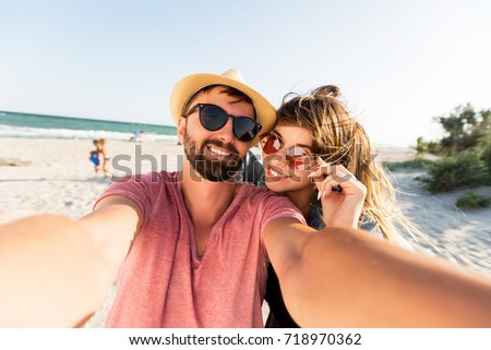 Traveling couple in love   making self portrait by digital camera , having fun on  amazing tropical beach.   Attractive wonder girl with   stylish hipster boyfriend enjoying holidays. 