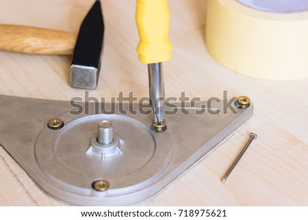 Screwdriver, scotch tape, hammer and nail. Hard work repairs. Wooden white table. Screws, bolts, nut and pins. Close up with hammering a nail.