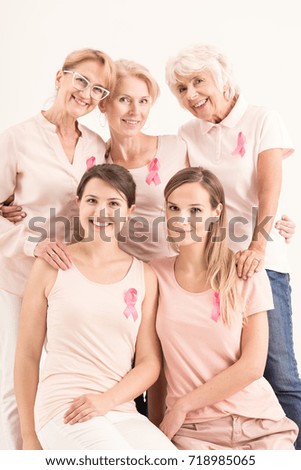 Women in pink shirts and pink ribbons are posing for a portrait picture. Breast cancer concept 