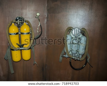 two old, retro, vintage, aged Aqualung or Scuba Oxygen Balloons hang on wooden wall. photo of yellow Diving Equipment. Underwater sport item. dive tool Royalty-Free Stock Photo #718992703