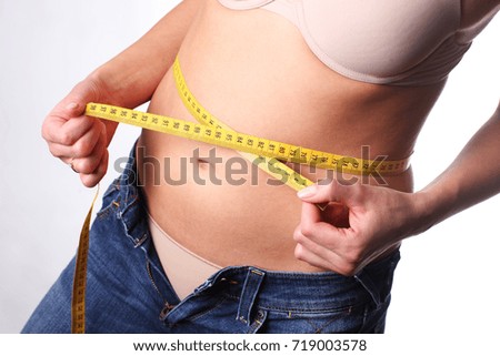 Gain weight. Young woman is checking her measurement. Fat belly.