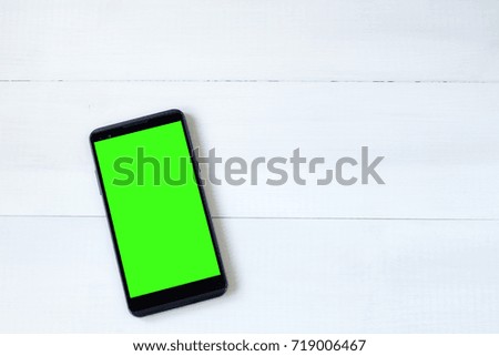 Cell phone with green screen on wooden desk. Mobile phone concept background.