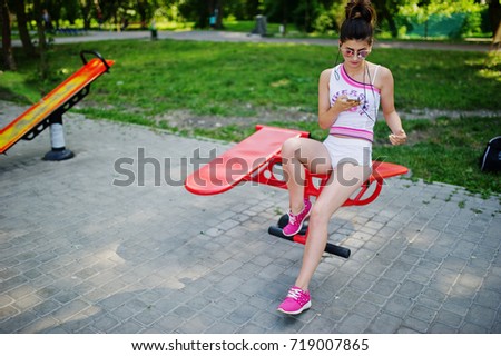 Sport girl wear on white shorts ans shirt doing exercises on simulators outdoor at park.