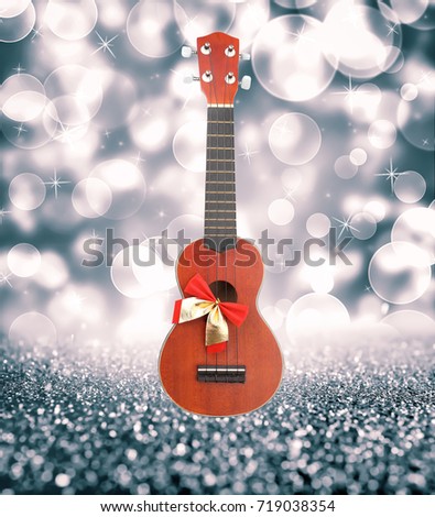 Christmas music concept. Guitar with ribbon bow on blurred background