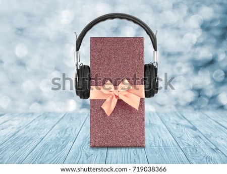 Christmas music concept. Gift box with headphones on blurred background