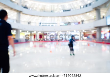 Abstract blurred the man teaching a boy playing skate at ice skating rink in the mall department store.