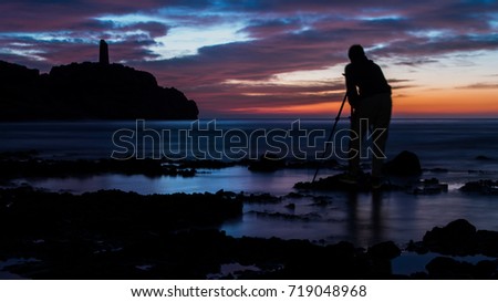 Person taking a photograph at sunrise in the beach