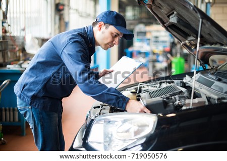 Portrait of a mechanic at work in his garage Royalty-Free Stock Photo #719050576