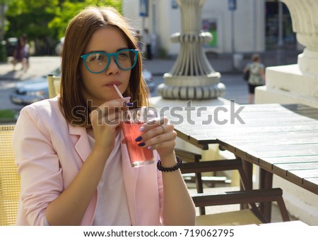 Young pretty girl drinks a cold beverage, outdoor