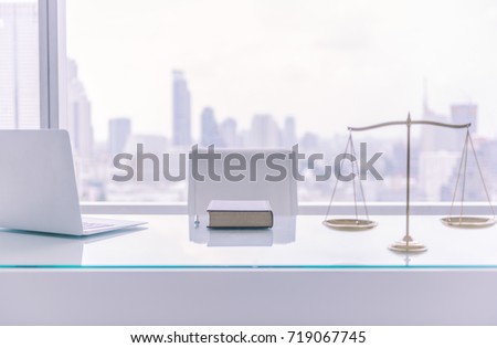 law books,computer and scales of justice on desk in lawyer office and city view. Royalty-Free Stock Photo #719067745