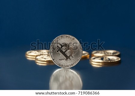 A few gold and silver   coins bitcoin lie on a blue backgroundConcept of crypto currency