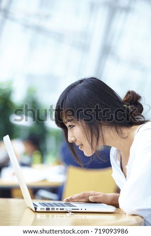 one pretty young Chinese college student in library using laptop
