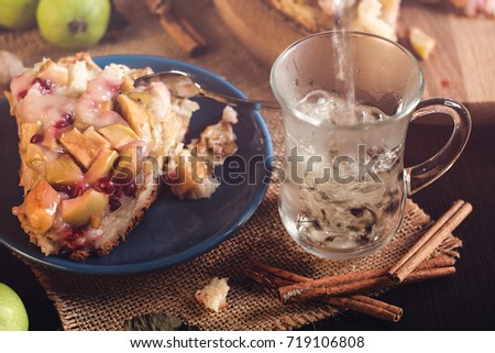 Homemade Apple pie on a round wooden board with green apples, cinnamon and red currants. Food concept. Low key image. An intimate, homely atmosphere. A beam of light on the cake and apples