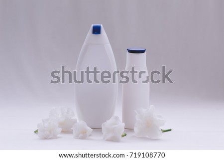 Two white bottle of cosmetic, shampoo , body lotion or perfume on white back ground with flowers - photography Mock up for your design