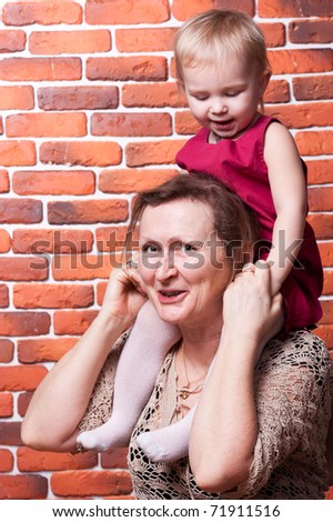 Grandmother with her grand daughter against brick wall