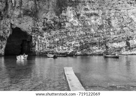 Pleasure boats at the rugged coastline delineated by sheer limestone cliffs, and dotted with deep caves on Malta. The Inland Sea is a lagoon of seawater on the island of Gozo. Black and white picture