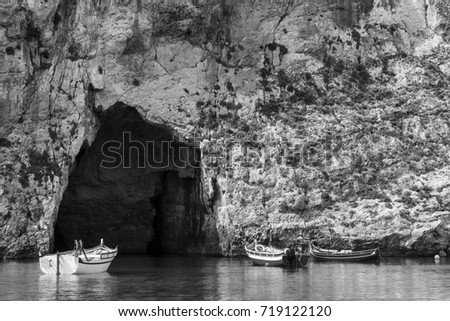 Pleasure boats at the rugged coastline delineated by sheer limestone cliffs, and dotted with deep caves on Malta. The Inland Sea is a lagoon of seawater on the island of Gozo. Black and white picture