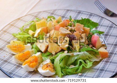 Healthy salad plate with apple, dried cranberry, walnut, spinach and poppy seed dressing on wooden background close up. Healthy food. Clean eating. Nutritious Vegetable Salad with Boiled Egg Slices.