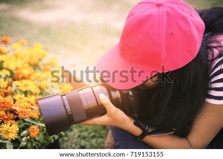 Girl taking photograph of yellow flower using macro lens.