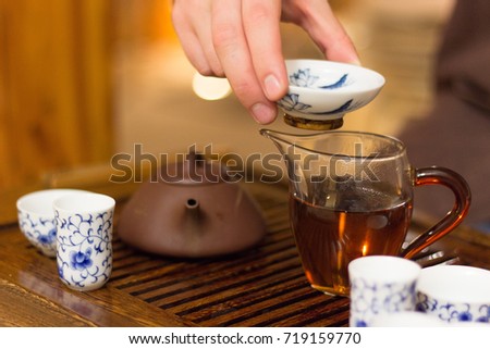 Hand of the master keep the cup. Traditional Chinese tea drinking ceremony. 