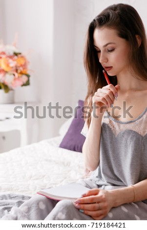 Beautiful young woman makes notes in writing book in the morning. Diary and dreams record, memories and thoughts, to-do list for day, close up