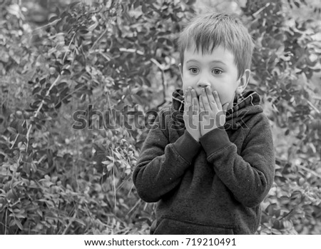 A scared closeup facial expression of a Caucasian child, black and white image. Afraid of punishment, bad behavior, severe punishment, scared kid, caught on lie, overwhelmed child stock image.