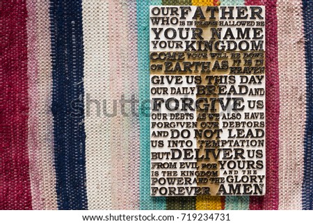 Wooden carved word of the Lord's Prayer on the  colored striped carpet background.