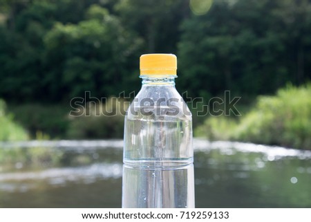 A bottle of water with yellow cap on nature background. Environmental concept.