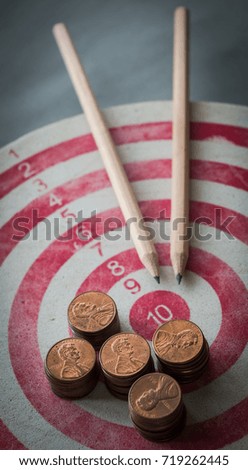 One cent coins stacks place on old dartboard with pencils