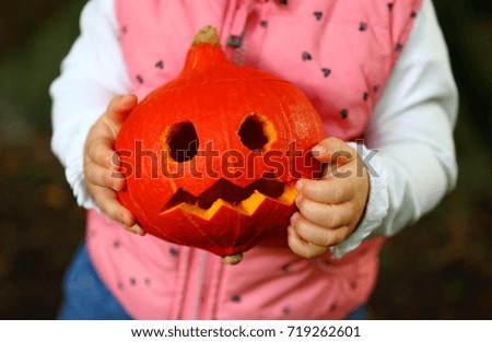 Child hands with halloween pumpkin. Treat or trick tradition with halloween curved pumpkin