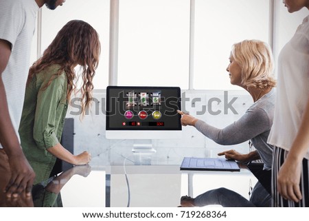 Slot machine with symbols and  icons on mobile screen against colleagues looking at computer monitor during discussion
