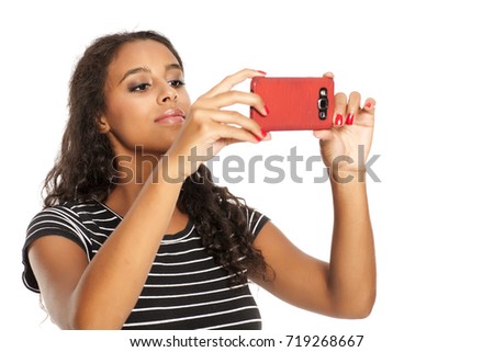 Young and happy dark skinned girl taking photos with her smartphone