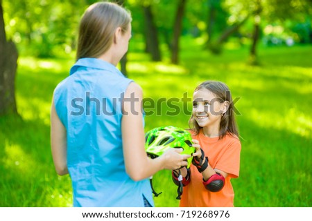 Mom gives his daughter a helmet for a safe ride on roller skates