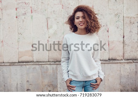 Curly haired girl with freckles in blank grey sweatshirt on the street. Mock up. Royalty-Free Stock Photo #719283079
