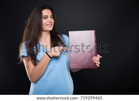 Cheerful girl student pointing at her album after finising school