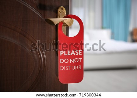 Open door with sign PLEASE DO NOT DISTURB on handle at hotel