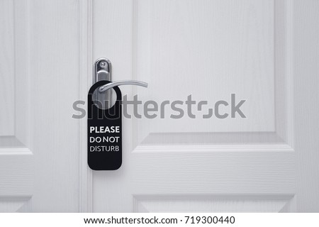 Closed door with sign PLEASE DO NOT DISTURB on handle at hotel Royalty-Free Stock Photo #719300440