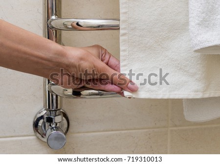 Chrome towel rail. A woman is holding a towel. Cropped image.