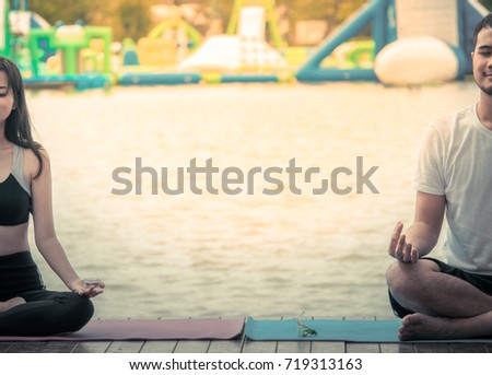 The acting setup of Yoga concept. A asian young man and woman doing Yoga outdoor by the lake.