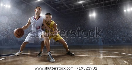 Basketball players on big professional arena during the game. Players fight for the ball. Players wearing unbranded clothes.