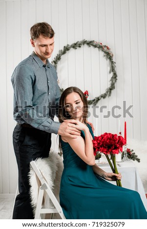 A gentle picture of an elegant girl with a red bouquet being hugged by her husband.