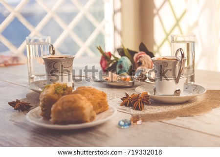 Two cups of Turkish coffee and plate with baklava lukum in lukumluk decorative flowers and badyan on a sunny day on a wooden table vintage toned picture close-up shallow depth of field