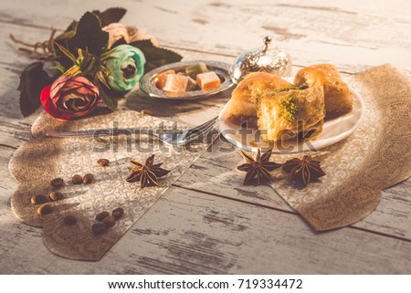 plate with baklava and lukum in lukumluk decorative flowers and badyan on sunny day on wooden table toned picture close-up shallow depth of field