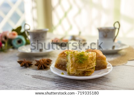 Two cups of Turkish coffee and a plate with baklava lukum in lukumluk decorative flowers and badyan on a sunny day on a wooden table vintage toned picture close-up shallow depth of field