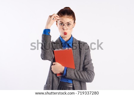 teacher with surprise on her face in her hand notebook on a light background                               
