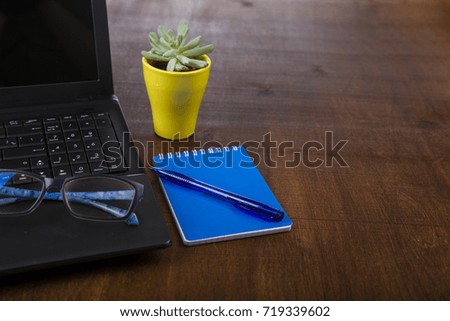 Workplace of  businessman with a laptop. On the table are  laptop, notebook, pen, glasses and plant