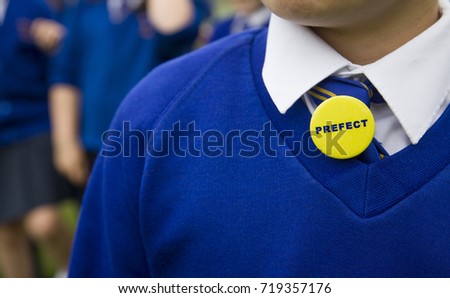 Young person in blue school uniform with a prefect badge Royalty-Free Stock Photo #719357176